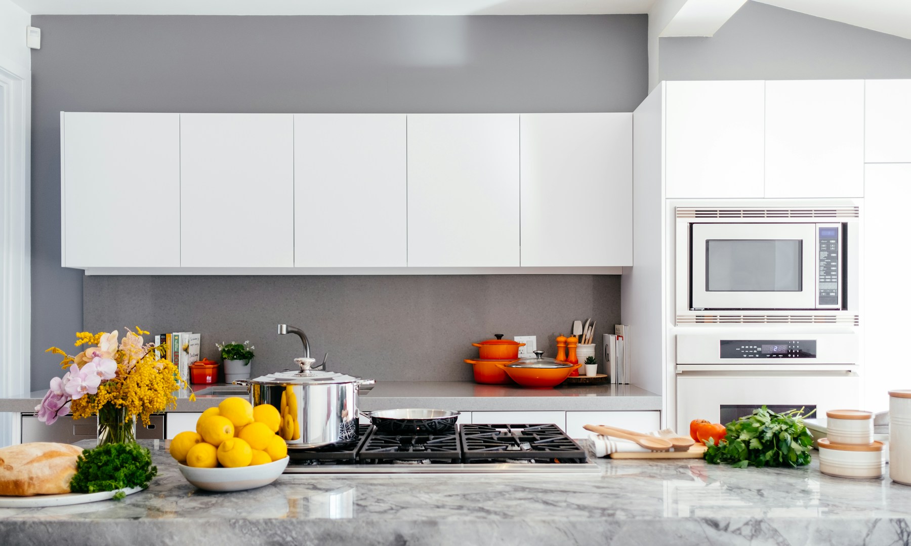 A bright kitchen with fresh produce, cookware and a marble counter
